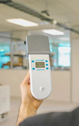 Hand holding Aeroguard Series 500 air quality monitor displaying PM2.5: 0.000.