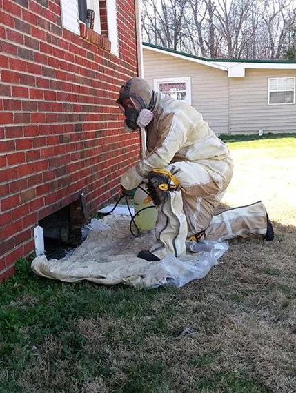 Technician in protective gear performing basement wall stabilization work.