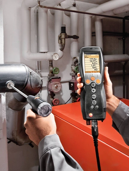 Technician using a flue gas analyzer to test boiler emissions.
