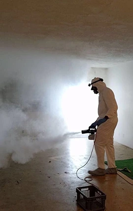 Man in hazmat suit fogging room for insurance help, using a fogging machine.