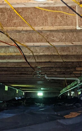 Crawl space with black vapor barrier, exposed wiring, and floor joists.